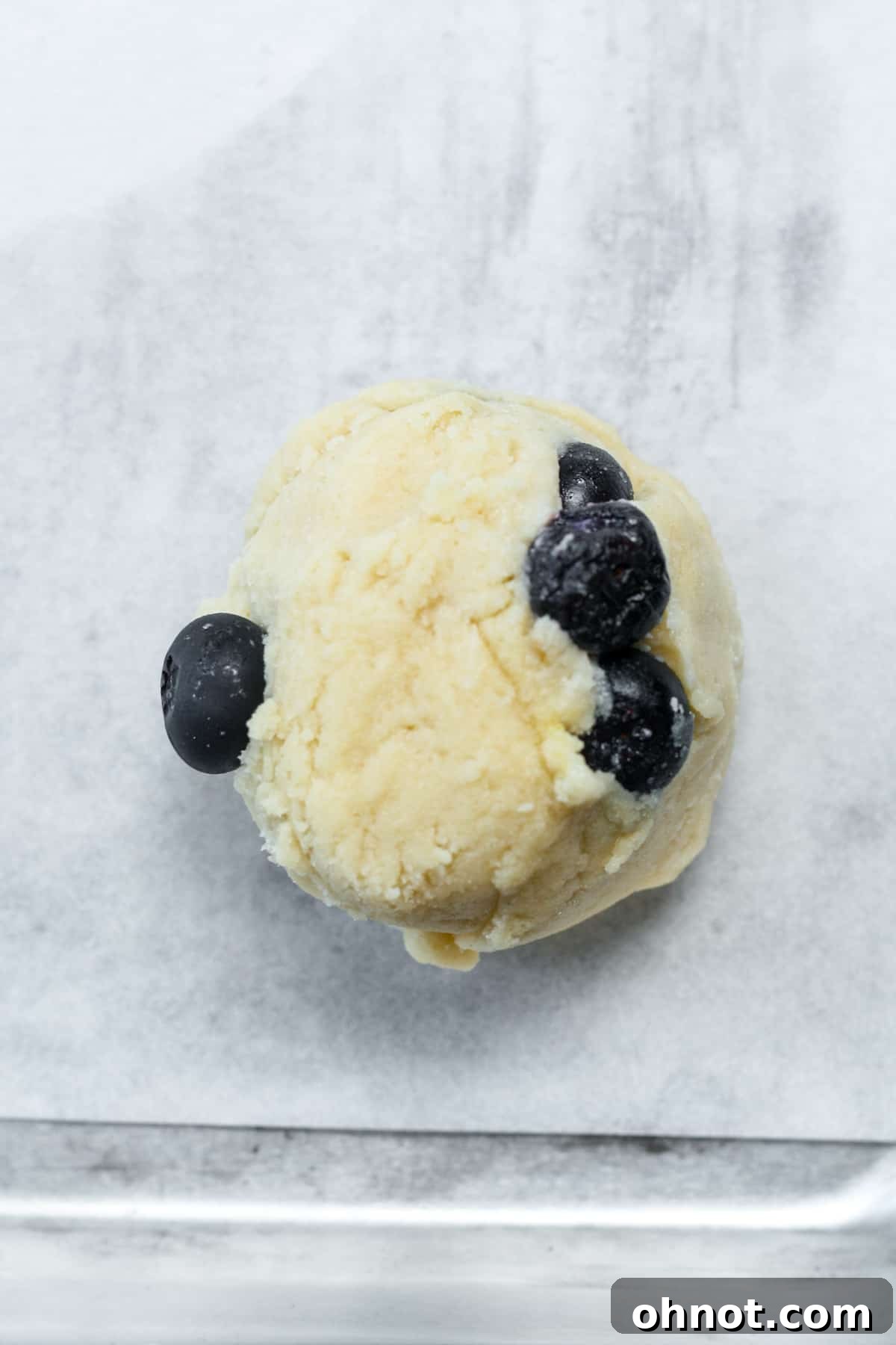 A ball of blueberry cookie dough with a visible indent in the center.
