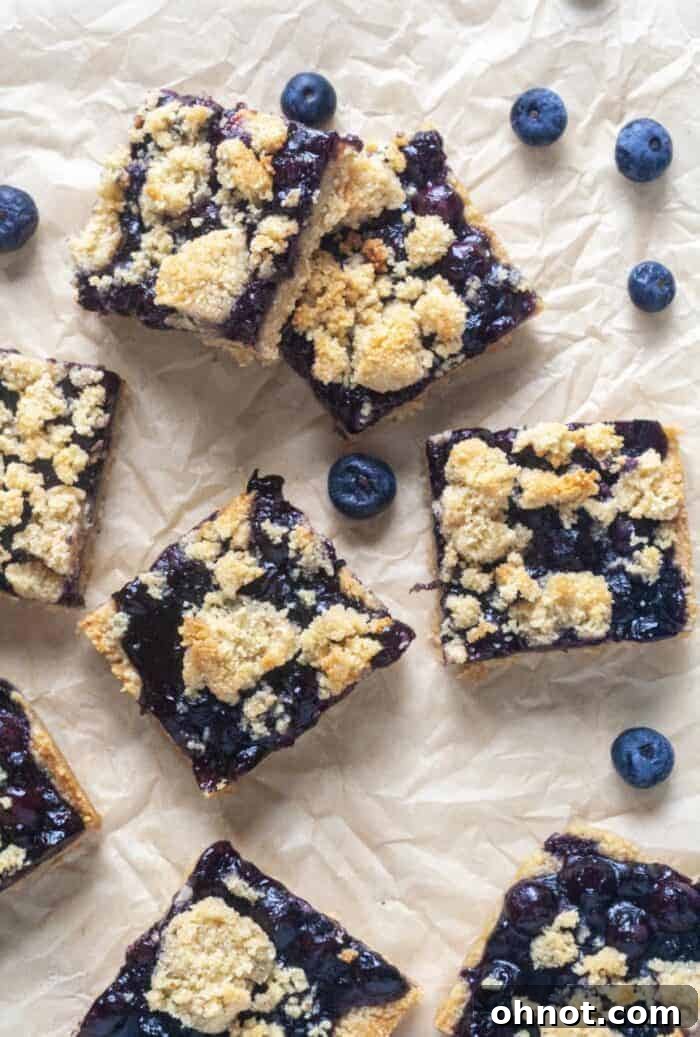 Several Paleo Blueberry Crumb Bars displayed on a sheet of parchment paper, highlighting their delightful layers and golden-brown crumble.