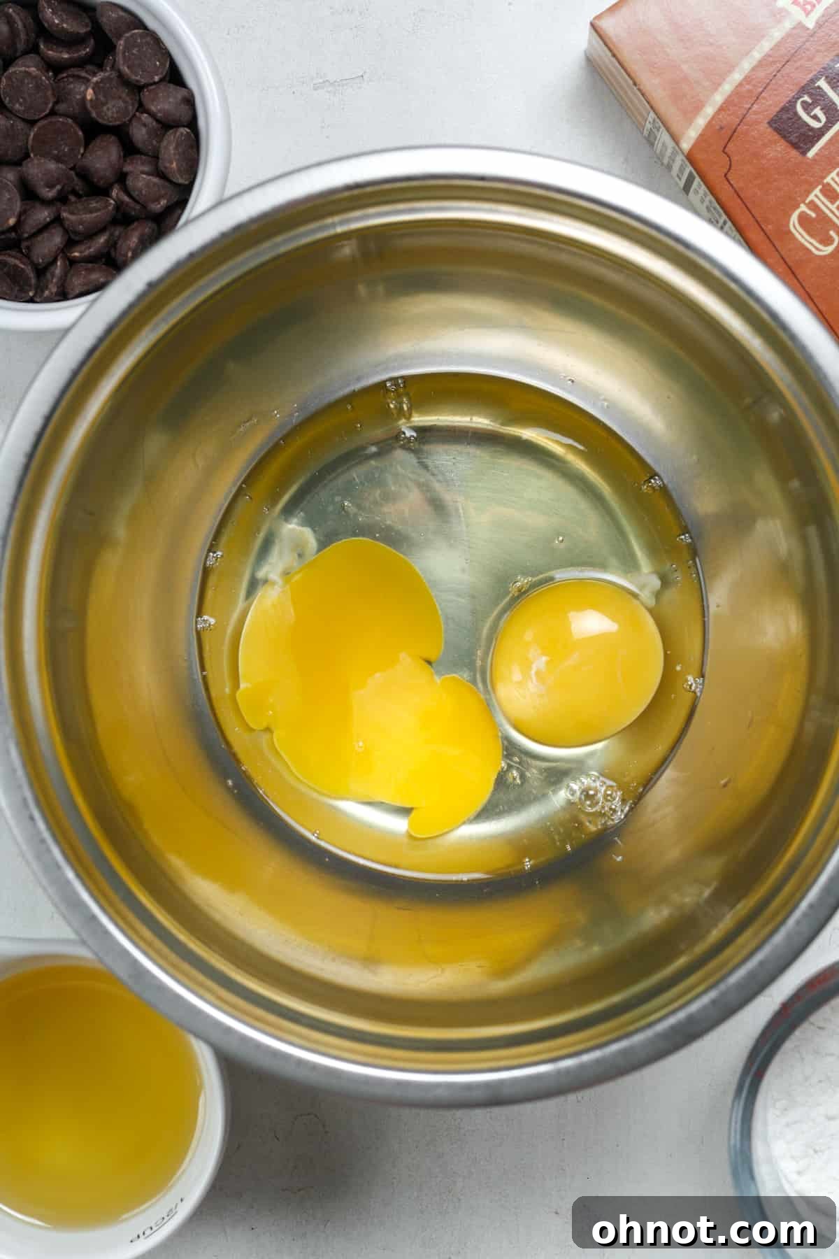 Two fresh eggs sitting in a clear mixing bowl, ready to be whisked.