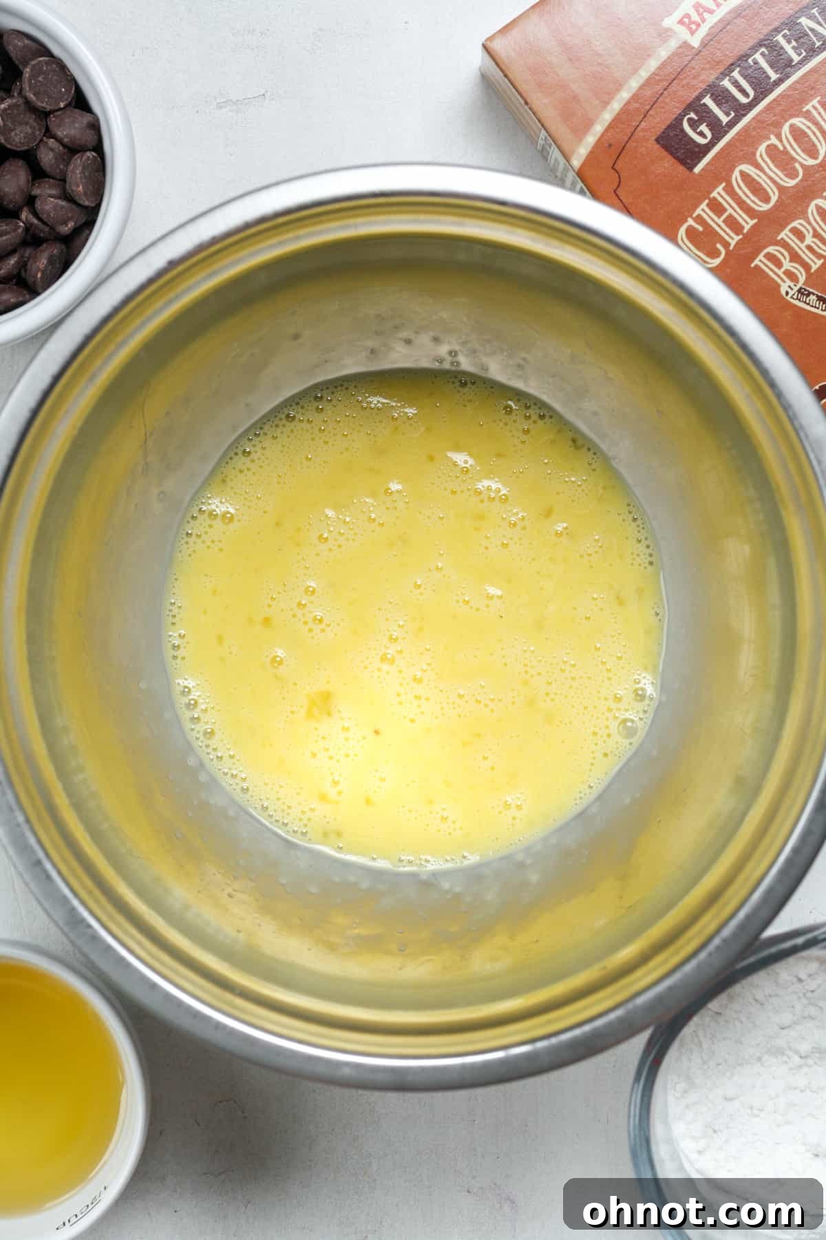 Close-up of vigorously whisked eggs in a bowl, showing a light, frothy texture.