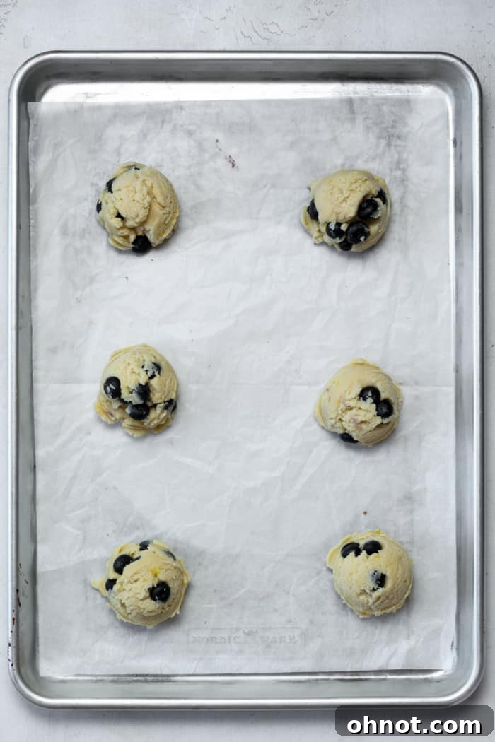 Raw cookie dough balls evenly spaced on a parchment-lined baking sheet