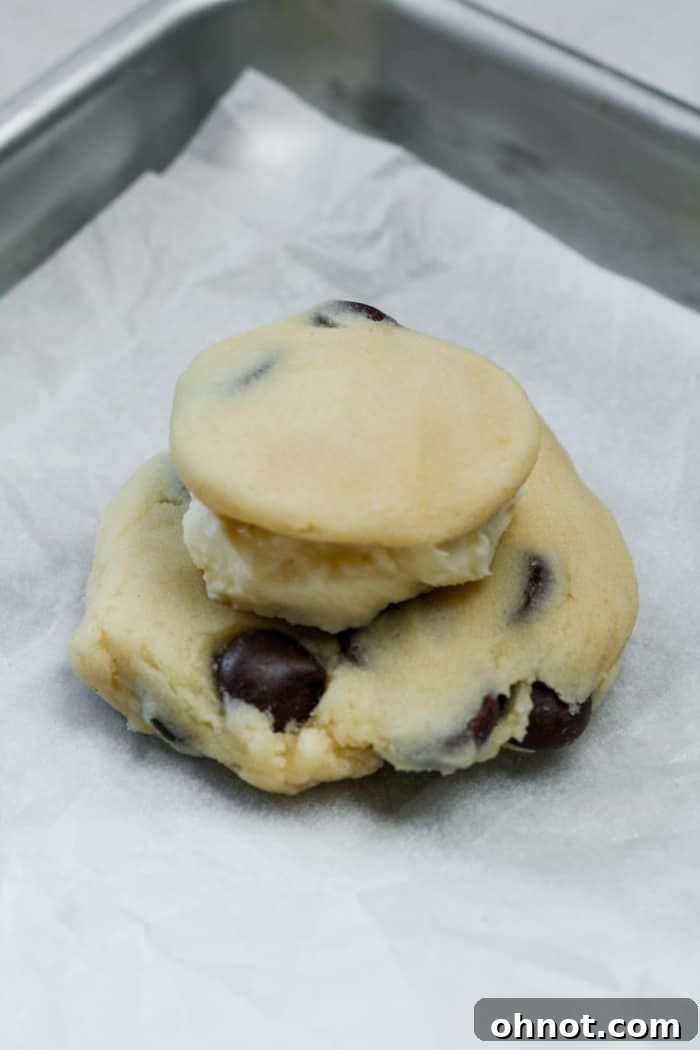A smaller cookie dough disc placed over the cheesecake filling, beginning to encase it.