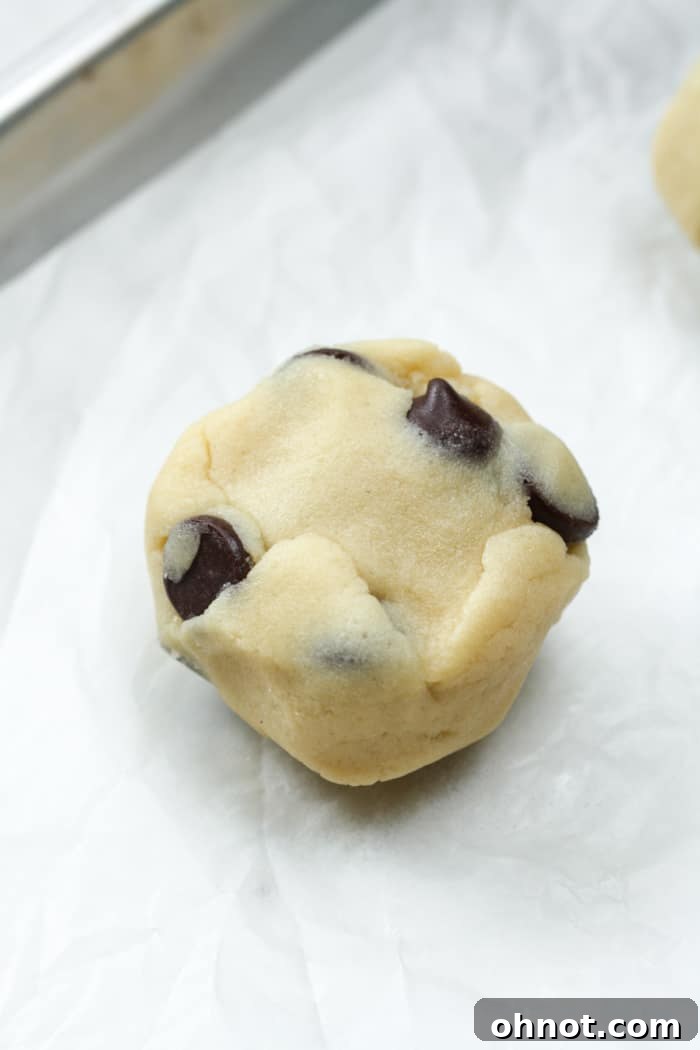A perfectly round, sealed cookie dough ball, completely enclosing the cheesecake filling.