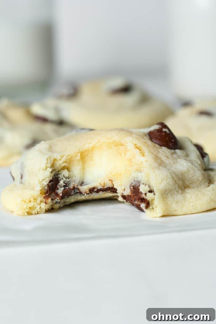 Irresistible gooey chocolate chip cheesecake cookies, cut open to reveal the creamy cheesecake filling and melted chocolate chips.
