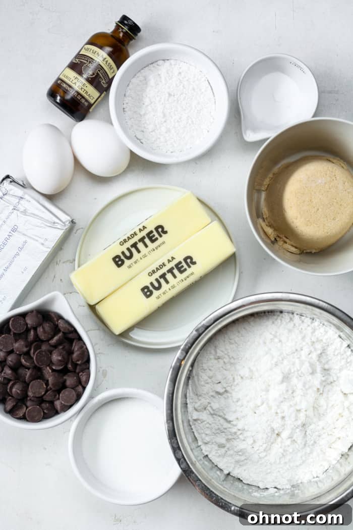 Assortment of baking ingredients including cold butter, cream cheese, sugar, and flour, ready for making chocolate chip cheesecake cookies.