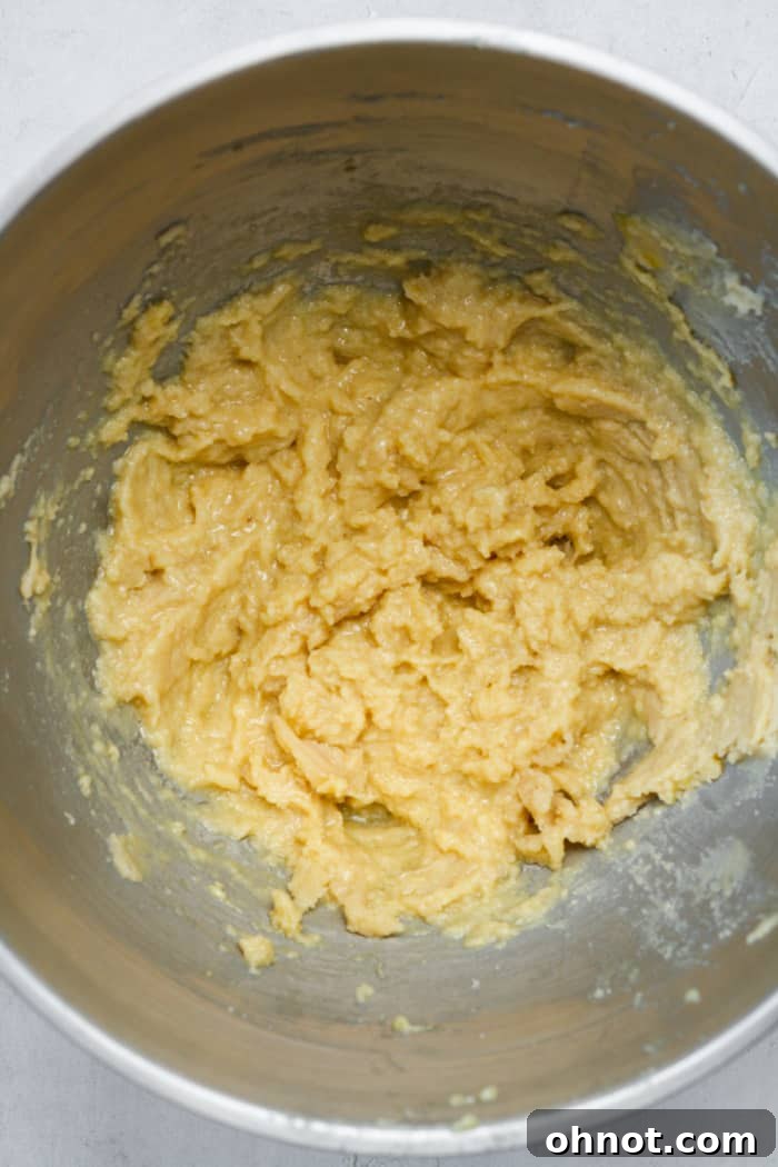 Eggs and vanilla extract added to the cookie dough mixture, being stirred.