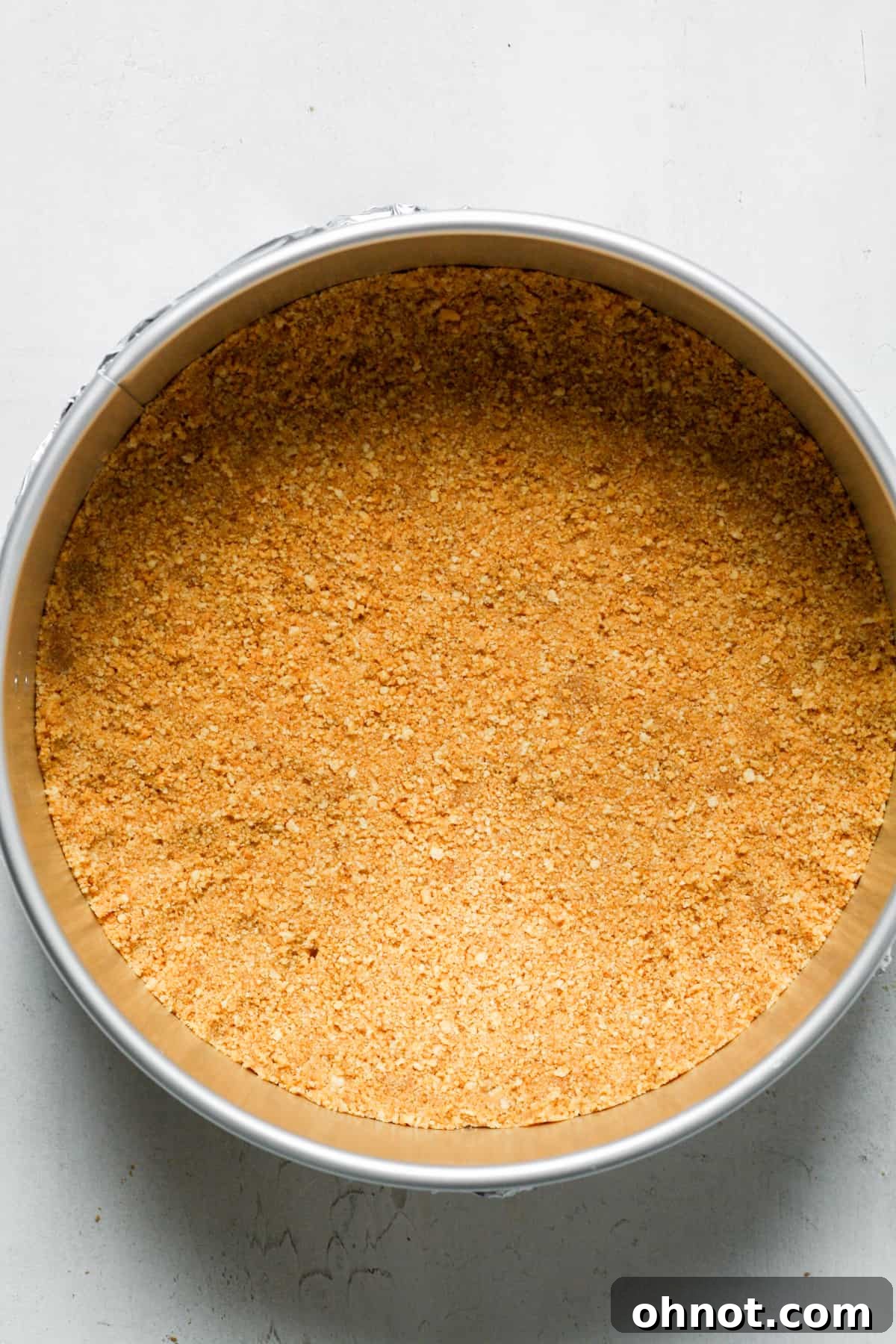 Shortbread cookie crust being pressed into a springform pan.