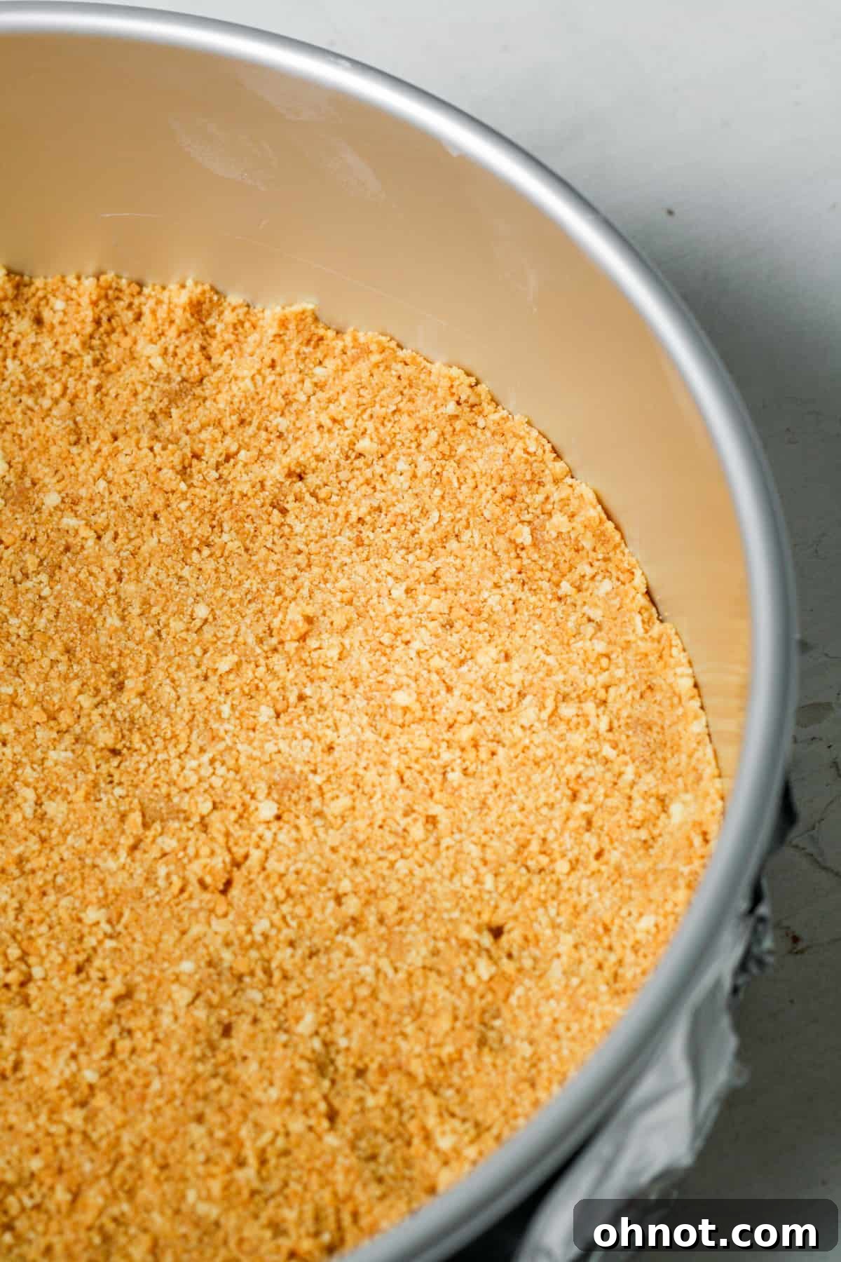 Cheesecake crust evenly pressed into the bottom of a springform pan.