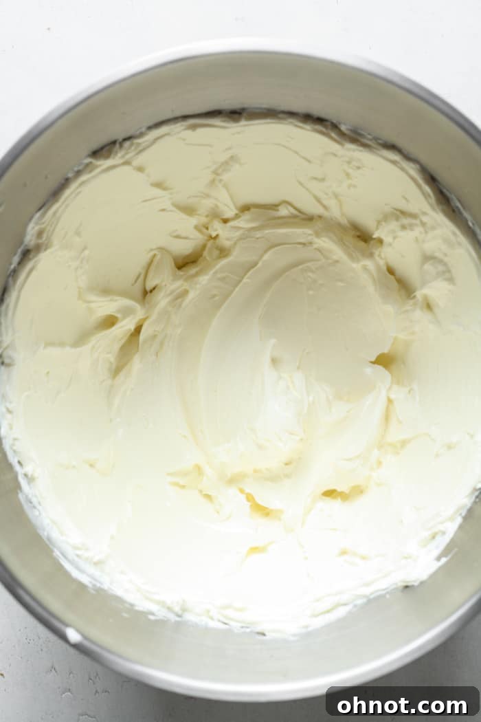 Smooth, beaten cream cheese in the bowl of a stand mixer.