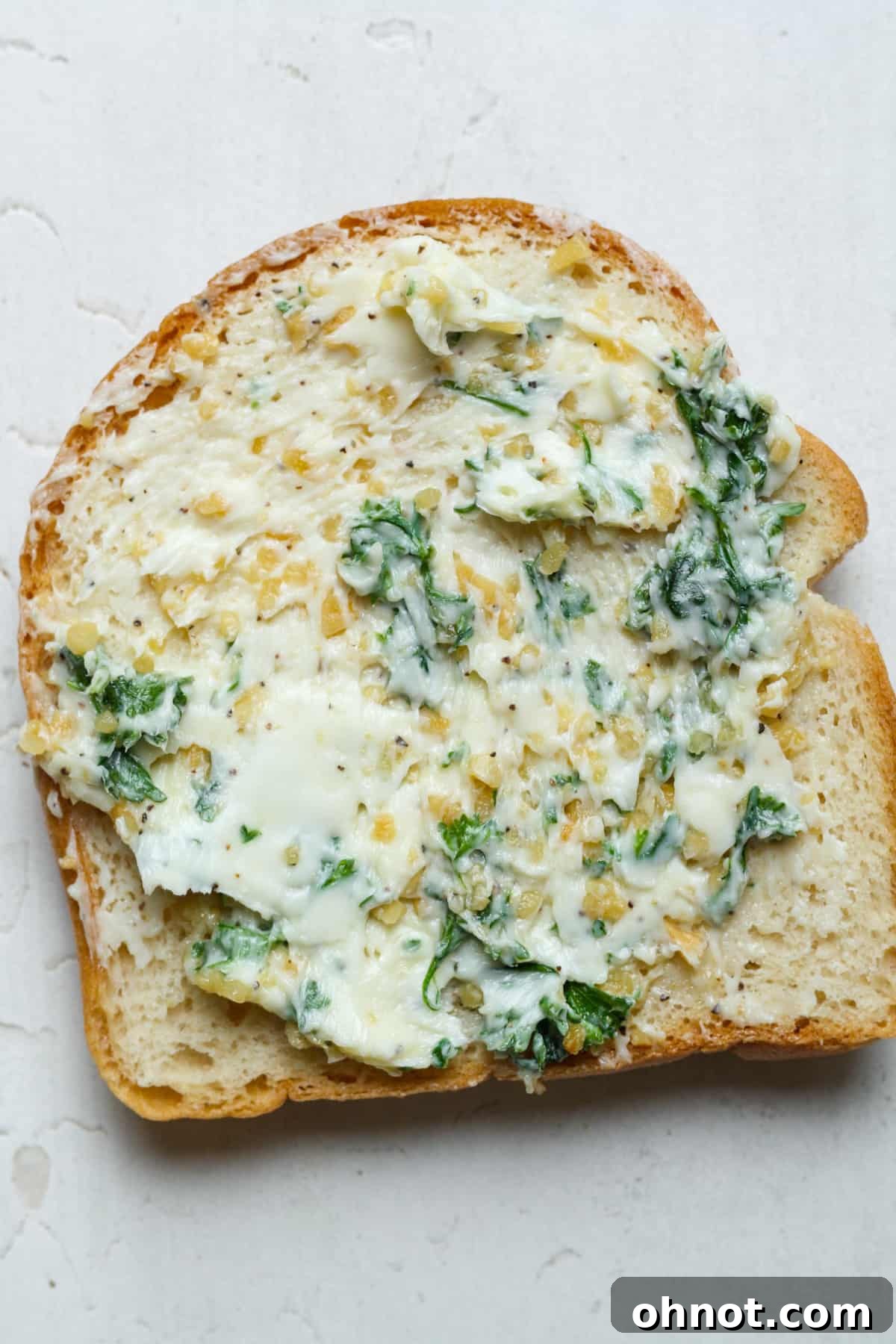 Individual slices of gluten-free bread generously coated with fragrant garlic butter, awaiting the oven.