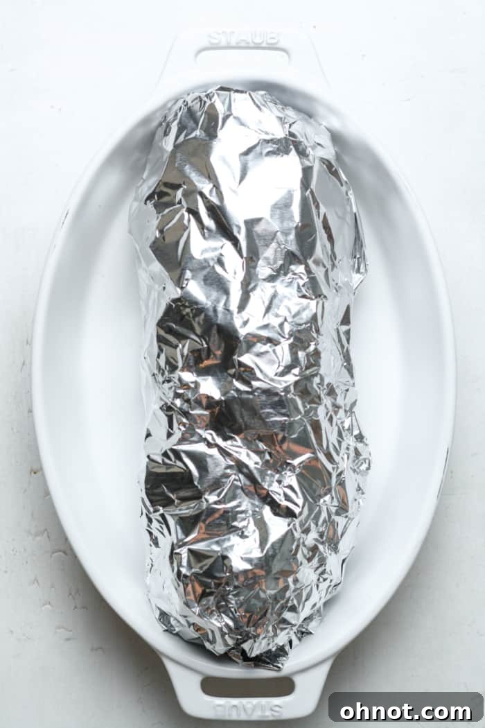 Gluten-free garlic bread wrapped in tin foil and placed in a casserole dish, ready for the oven.