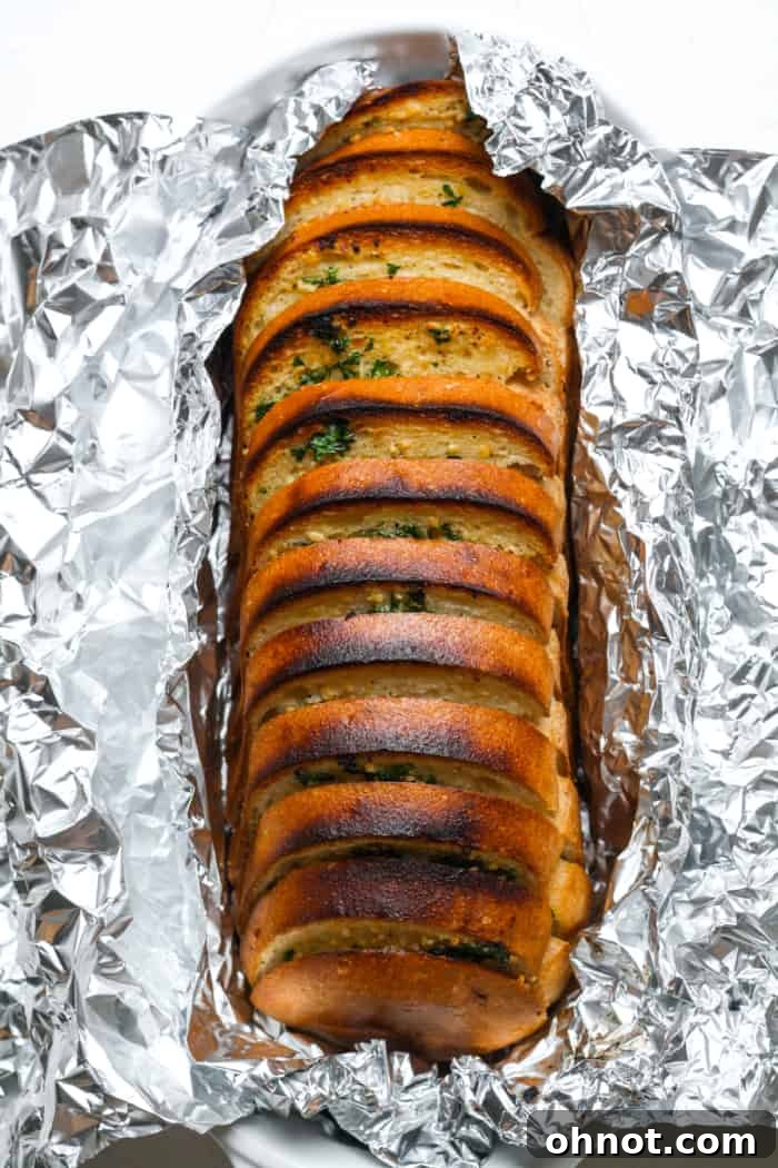 Crispy, golden gluten-free garlic bread just out of the oven, still in tin foil.
