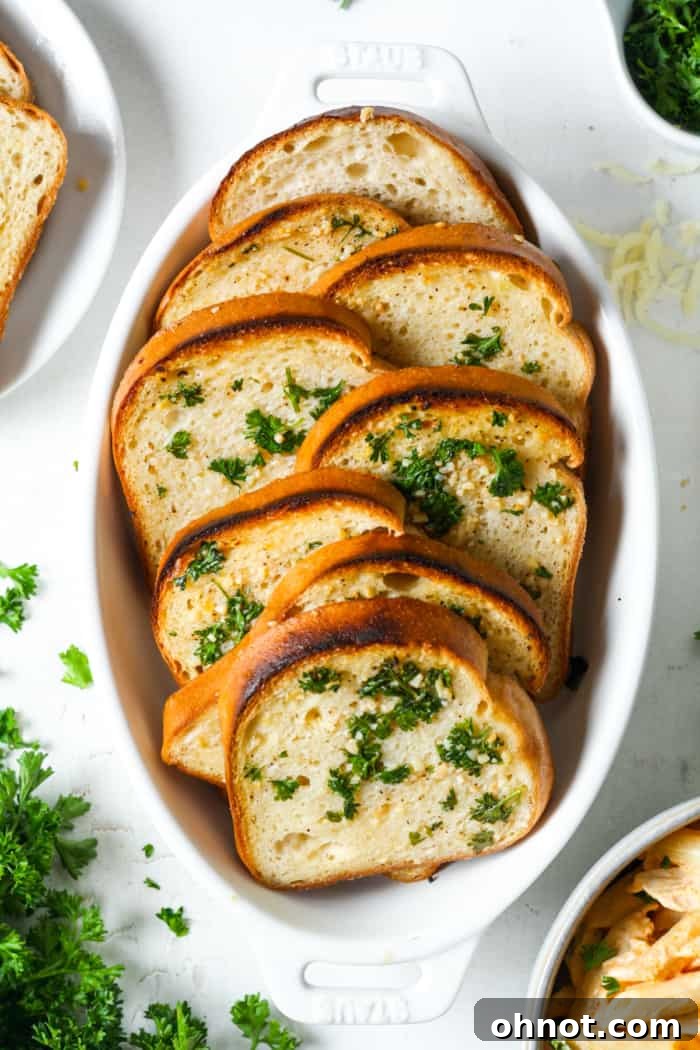 A dish of freshly baked gluten-free garlic bread, glistening with butter and herbs.