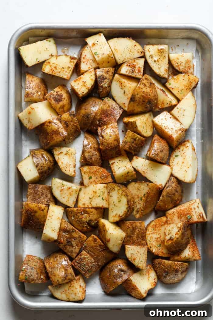 Seasoned potatoes spread in a single layer on a baking pan