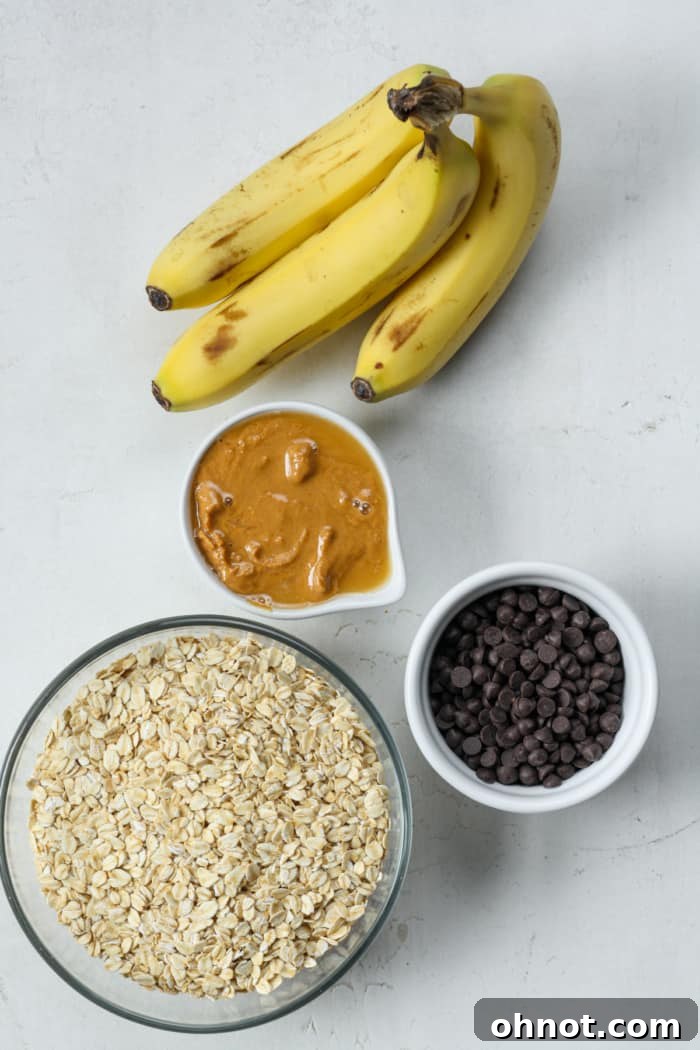 Four core ingredients laid out: bananas, old fashioned rolled oats, creamy peanut butter, and chocolate chips.