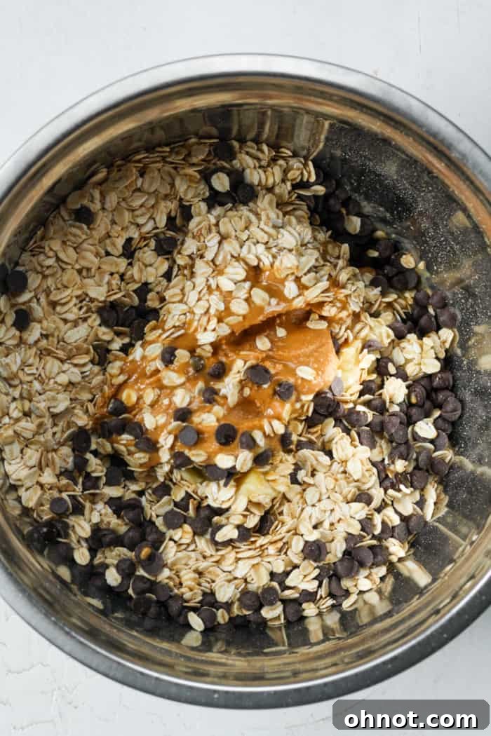 Mixing bowl containing mashed bananas and old-fashioned rolled oats before stirring.