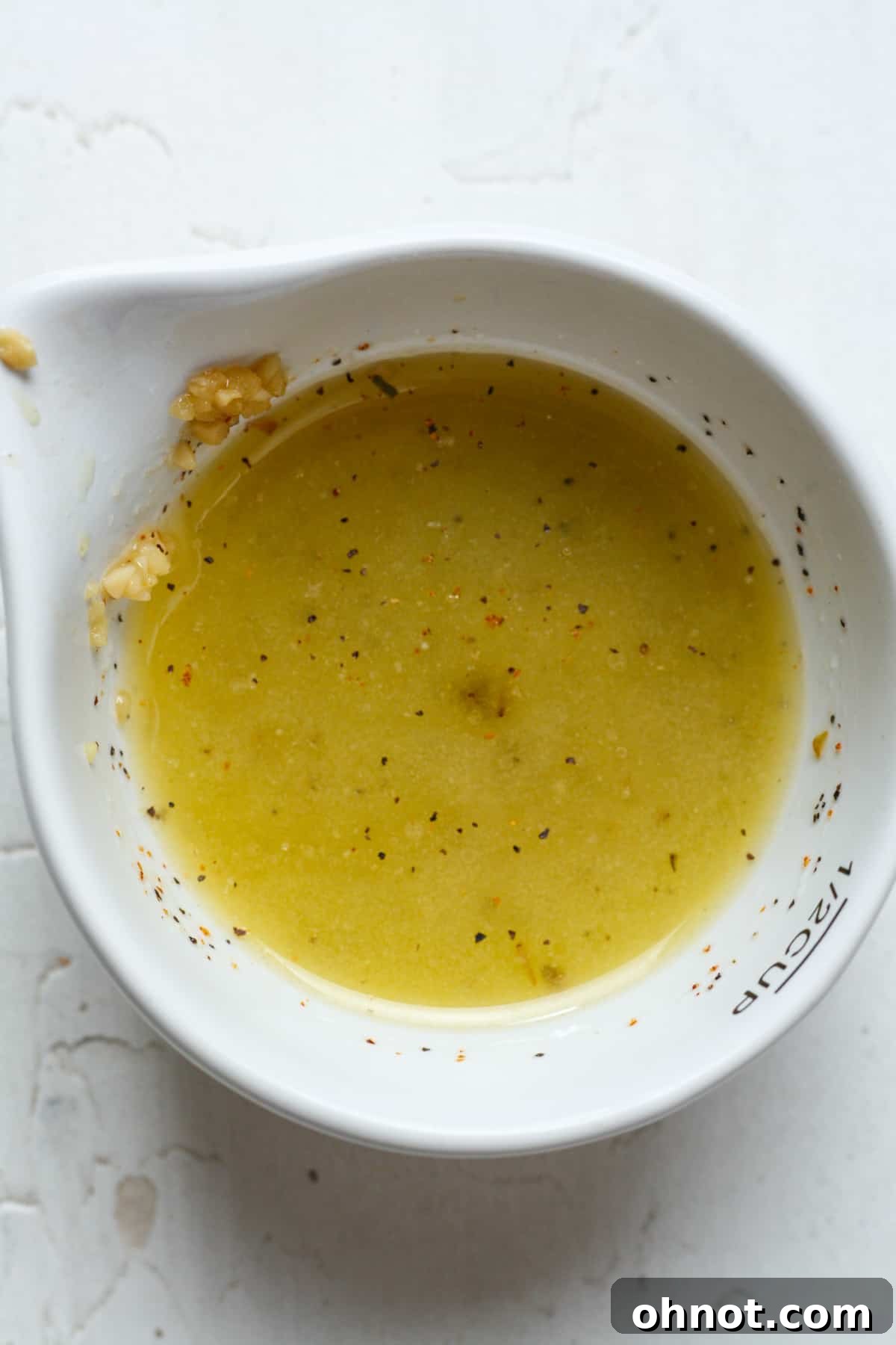 Close-up of a small bowl containing a vibrant garlic butter sauce with visible spices like paprika.