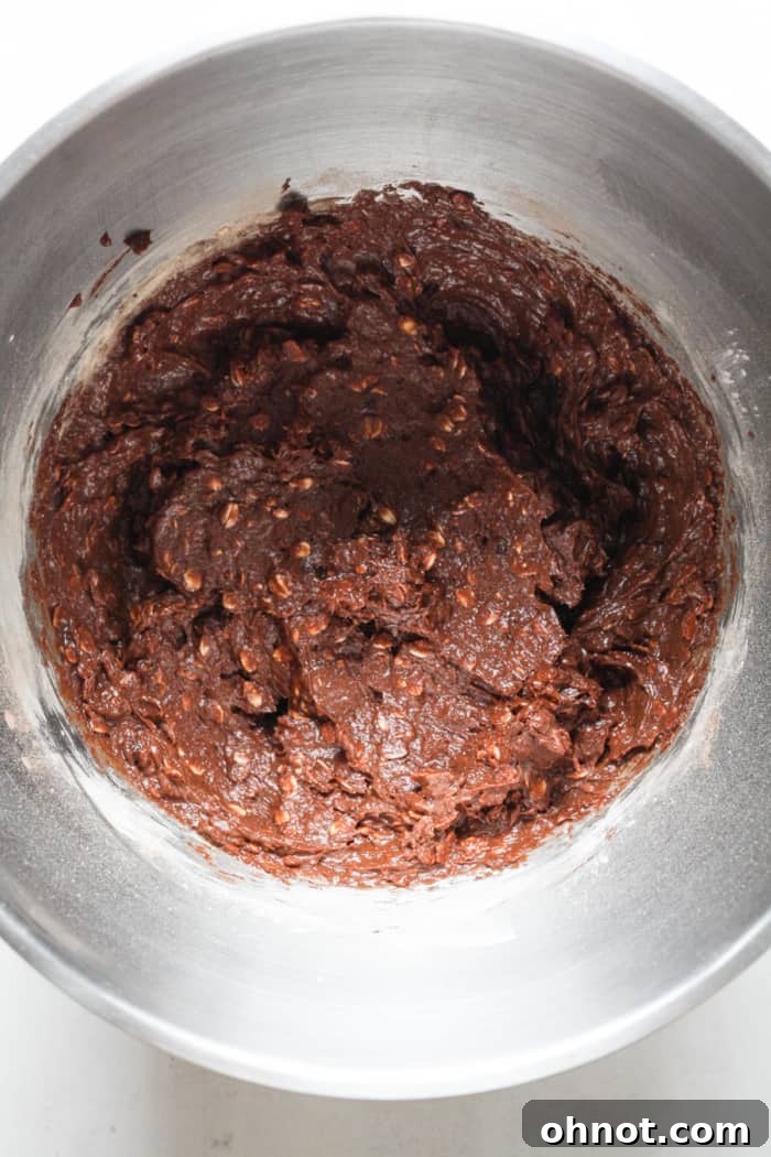 Brownie batter thickened with oats and other dry ingredients, ready for final additions.