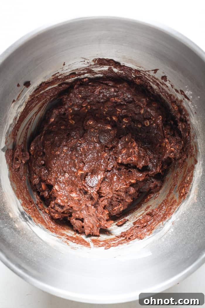 Rich chocolate chip brownie batter with additional chips folded in, showcasing its thick consistency.
