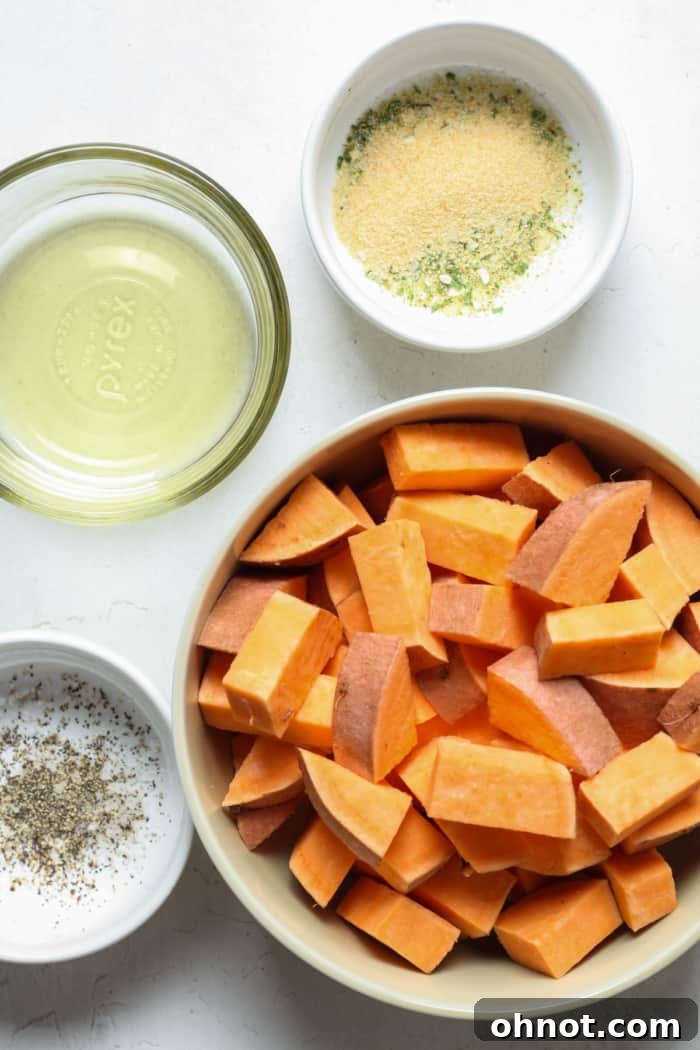 Diced sweet potatoes tossed with oil and seasonings in a bowl.