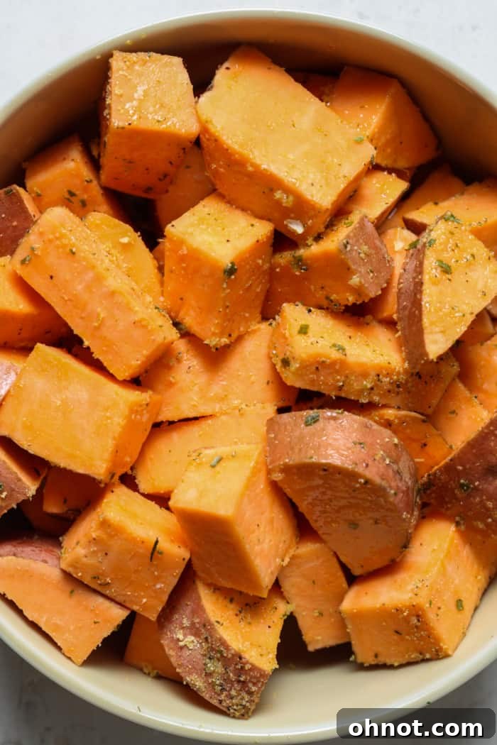 Bowl of diced sweet potatoes seasoned and ready for air frying.