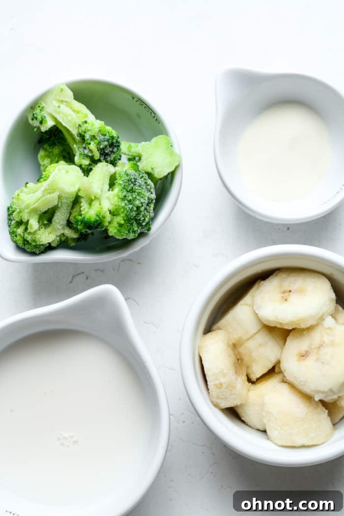 A selection of smoothie ingredients including frozen broccoli, various fruits, and a carton of milk on a kitchen counter.