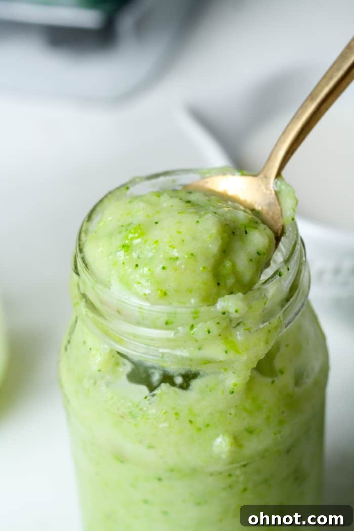 A thick, vibrant green broccoli smoothie in a glass jar, highlighting its creamy texture.