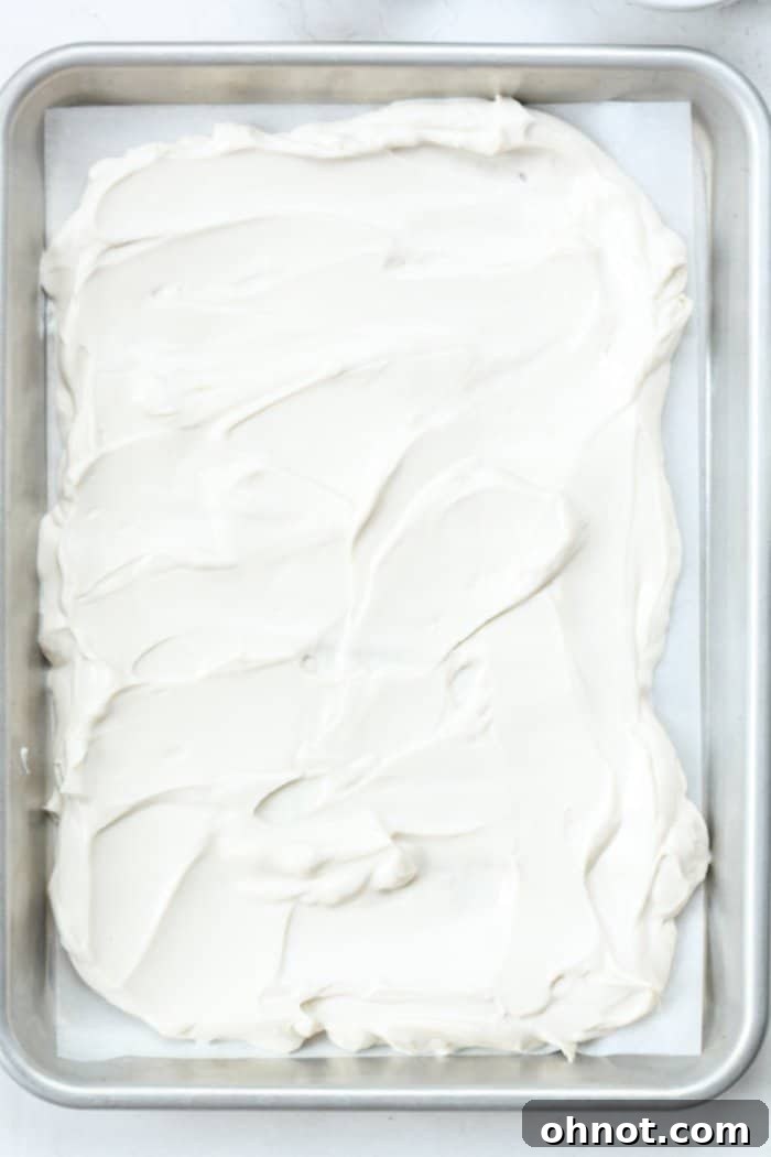 Smooth, even layer of yogurt spread on parchment paper in a pan.