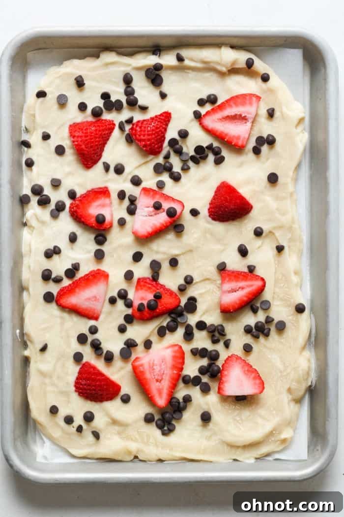 Greek yogurt bark base topped with colorful sliced berries and chocolate chips.