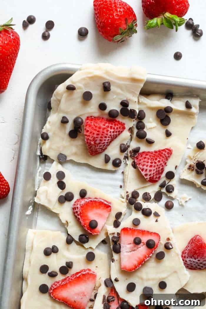 A baking pan filled with frozen yogurt bark, topped with an assortment of fruits and chocolate.