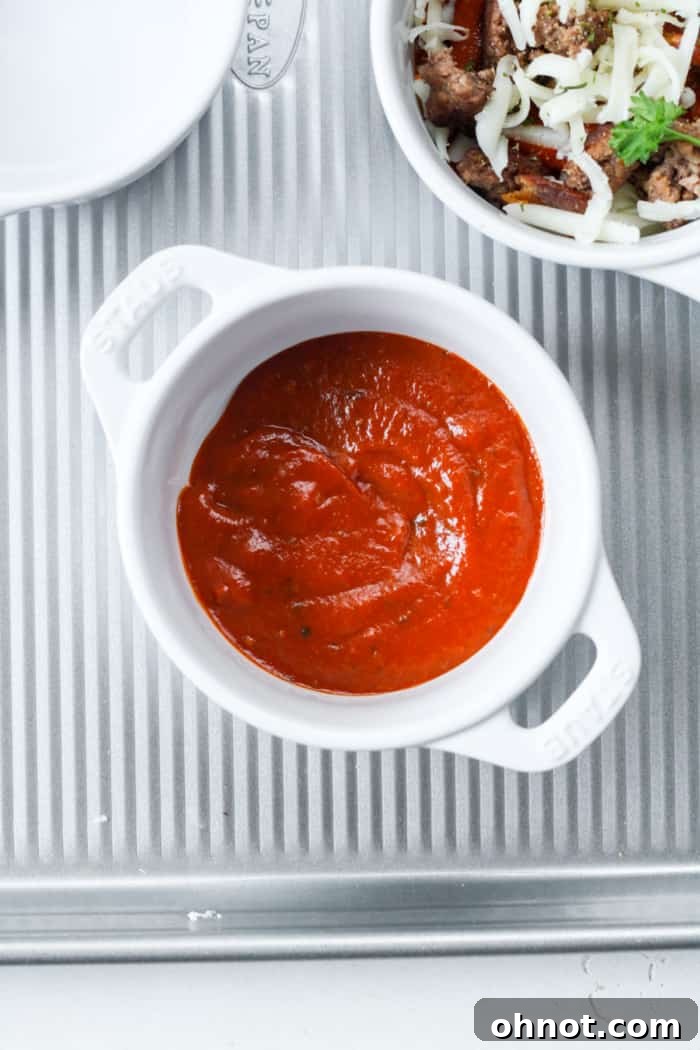 Individual ramekin with a generous scoop of vibrant red pizza sauce at the bottom.