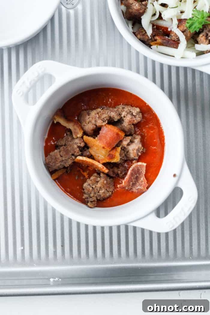 Ramekin now layered with cooked ground beef and crispy bacon bits over the pizza sauce.