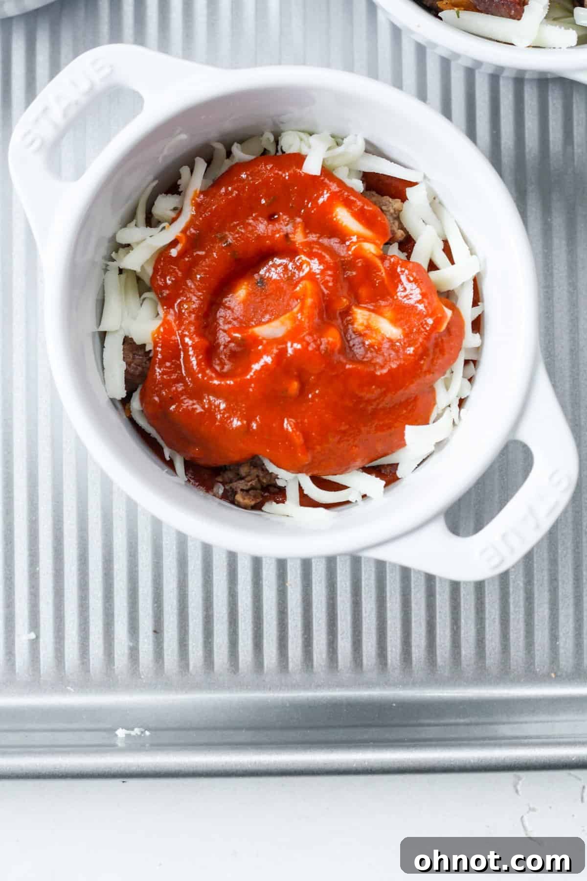Second layer of pizza sauce and melted cheese in a ramekin.