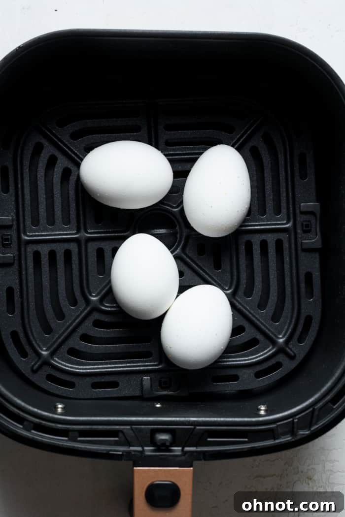 Eggs cooking inside an air fryer basket.