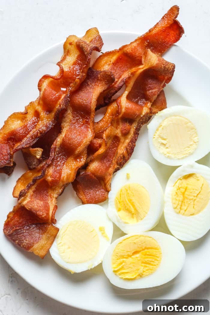 Crispy bacon served alongside air fryer hard boiled eggs, perfect for a hearty breakfast.