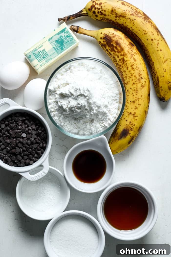 Various ingredients for gluten-free banana muffins, including ripe brown-spotted bananas, butter, maple syrup, eggs, and chocolate chips.
