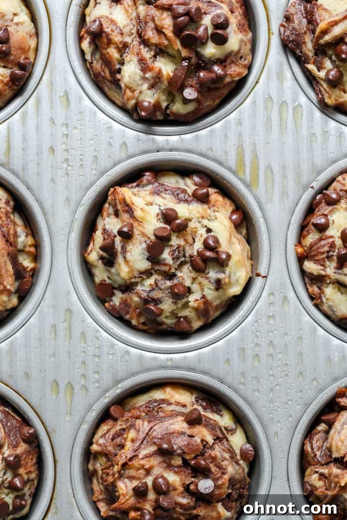 A tray of golden-brown, baked marbled banana muffins, fresh from the oven.