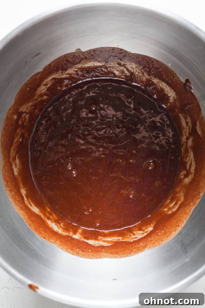 Melted chocolate mixture being stirred into the frothy egg and sugar mixture.