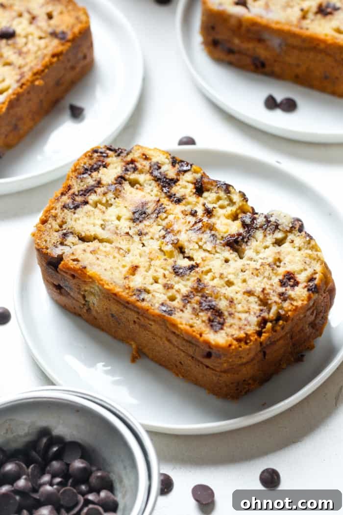 A thick, inviting slice of freshly baked dairy-free banana bread, showing its moist texture and optional chocolate chips.