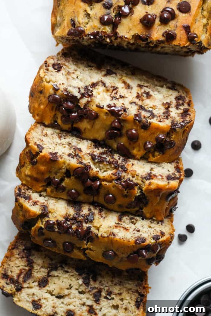 A freshly baked dairy-free banana bread loaf, studded with chocolate chips, on a cooling rack.