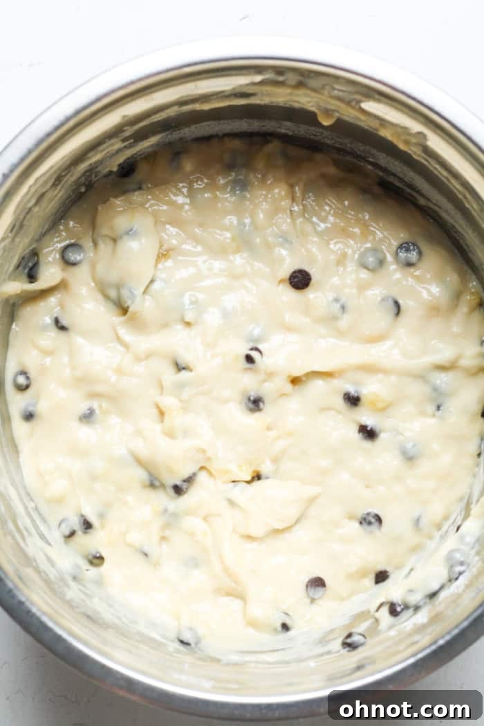 Rich banana bread batter with dairy-free chocolate chips gently folded in, ready for the loaf pan.