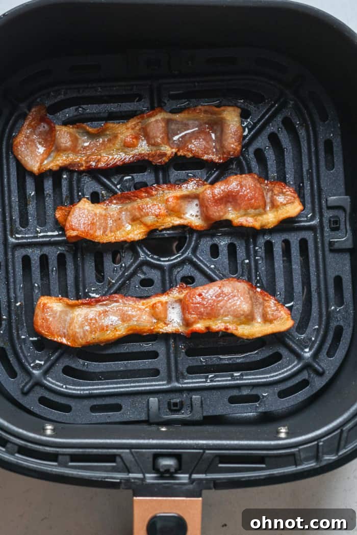 Crispy bacon cooking in the air fryer basket.