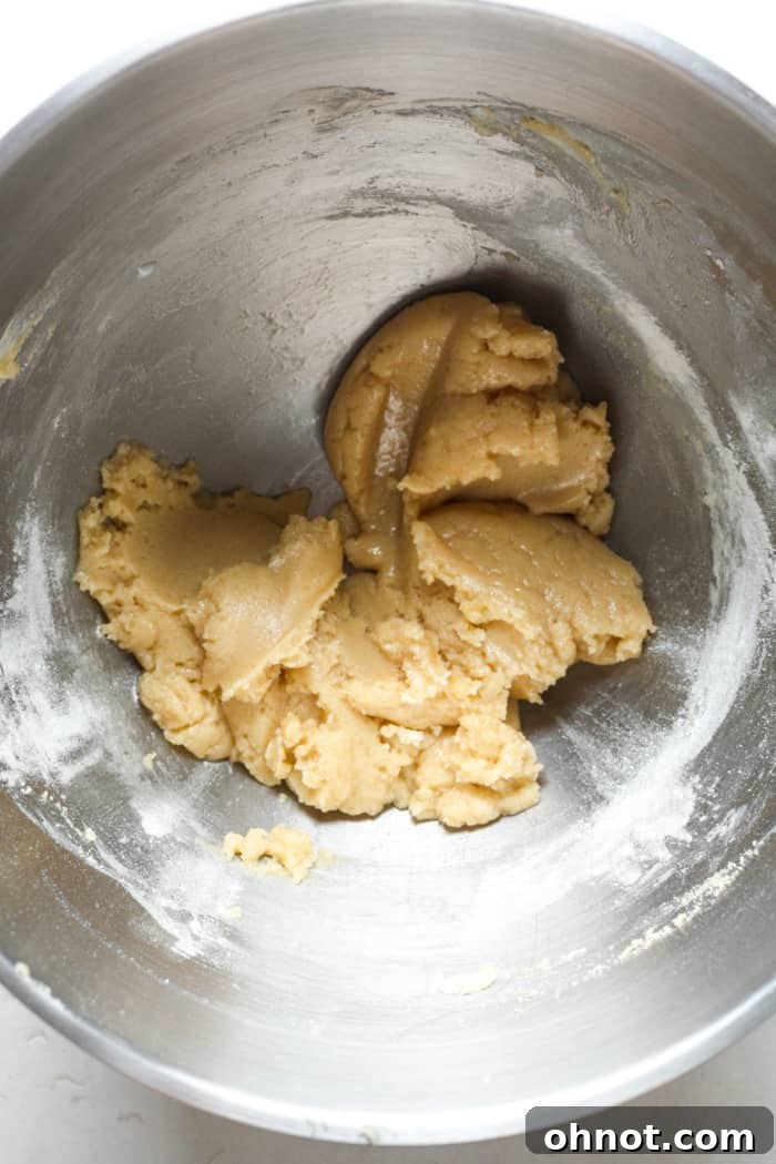 Soft cookie dough batter after adding flour, vanilla, and milk, ready for chocolate chips.