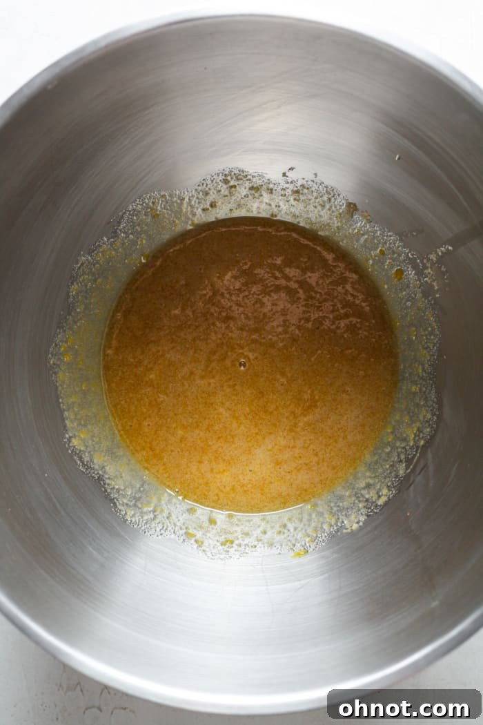Light brown sugar and eggs being vigorously whisked in a mixing bowl for aeration.