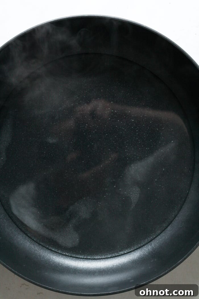 Close-up of fully dissolved sugar in water in a skillet, creating a clear simple syrup base for candying.