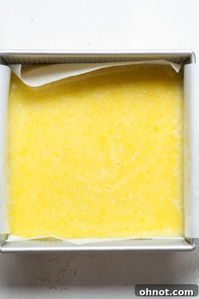 Lemon filling poured over the shortbread crust in the baking pan, ready for the oven.