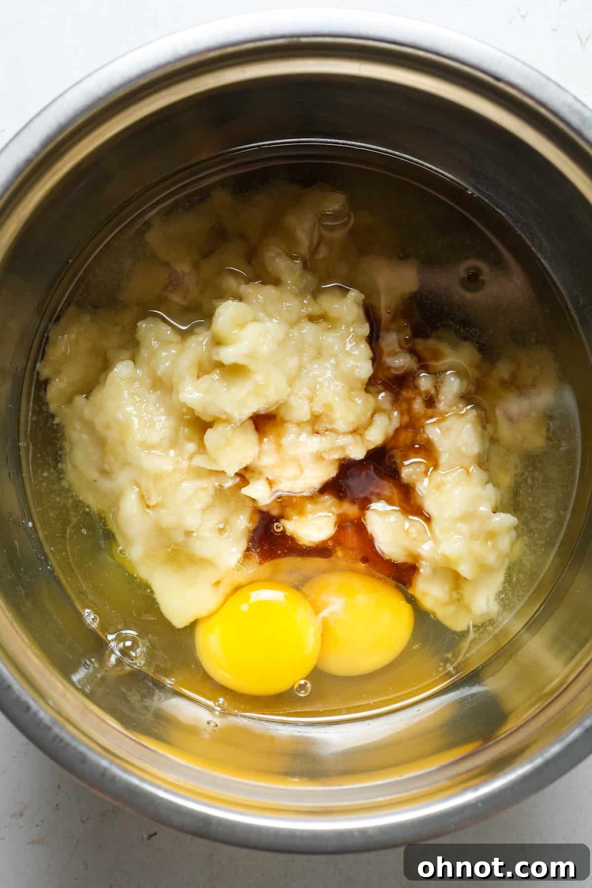 Mashed bananas, eggs, and vanilla extract in a mixing bowl.
