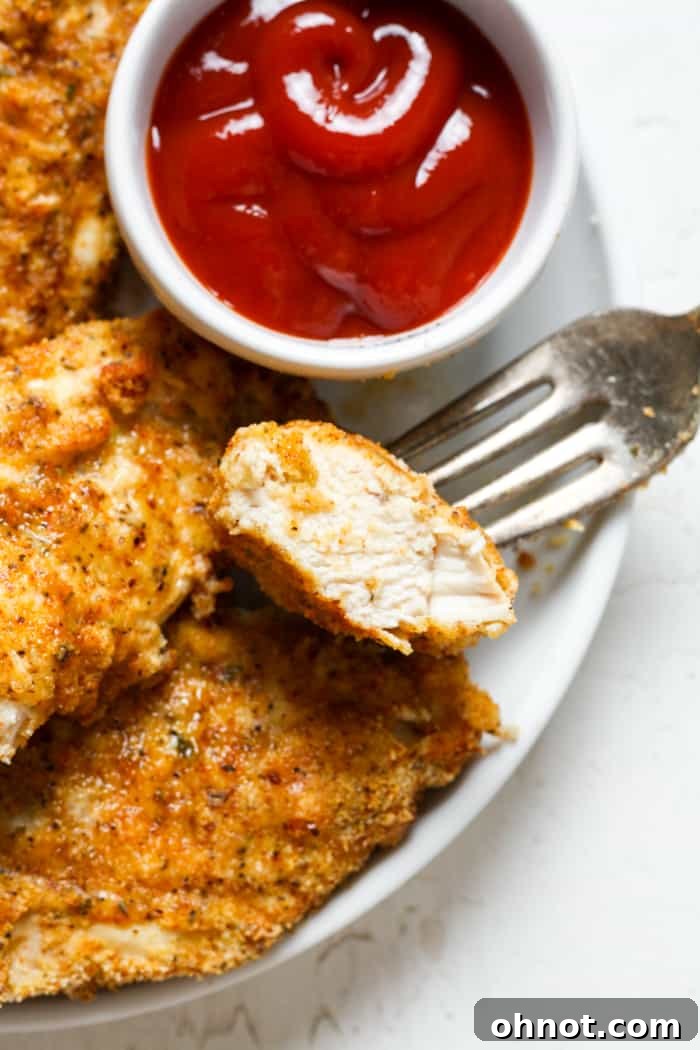 Close-up of juicy, breaded chicken tender showing its crispy texture.