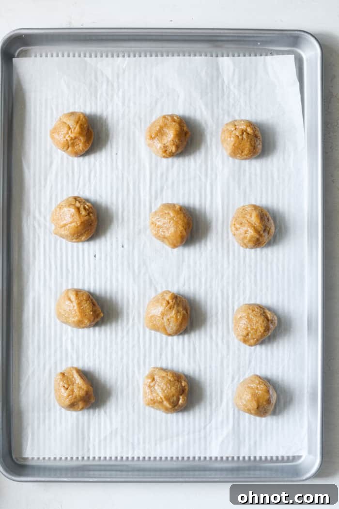 Uniform cookie dough balls neatly arranged on a parchment-lined baking sheet.