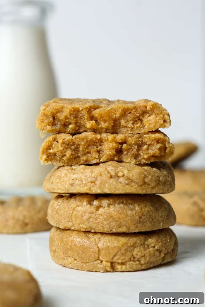 A stack of golden 3-ingredient cookies next to a jar of peanut butter.